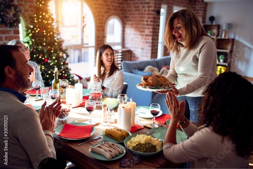 Family and friends dining at home celebrating christmas eve with traditional food and decoration  showing proud turkey cooking