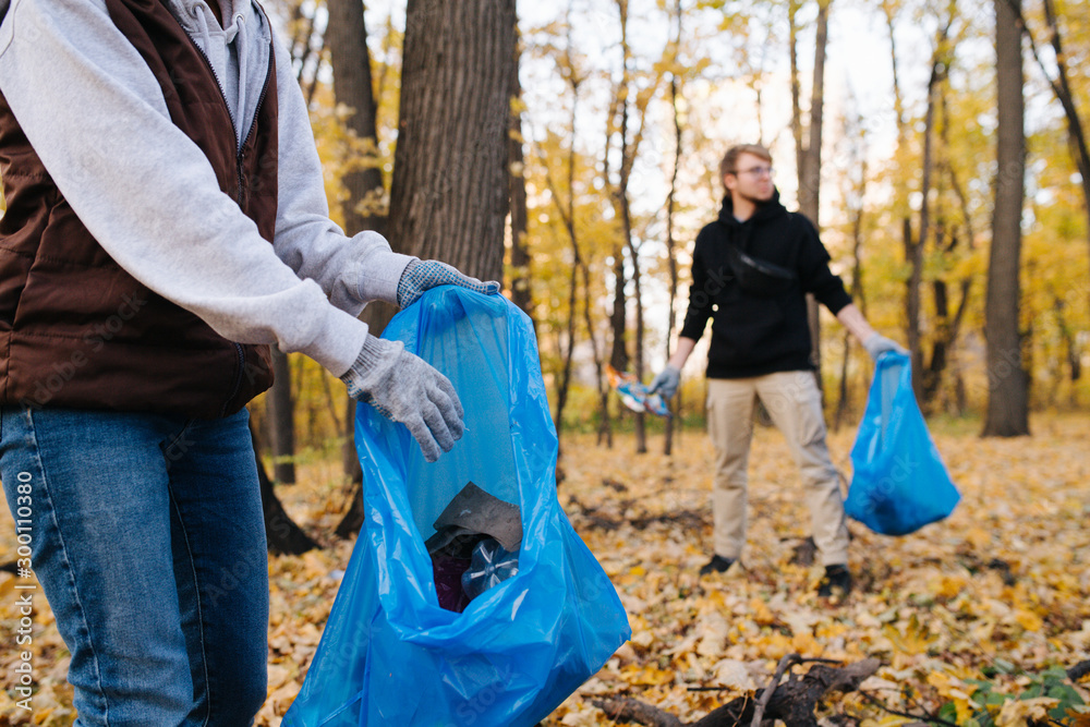 Φωτογραφία Close up of a group of volunteers collecting trash in seasonal forest at autumn