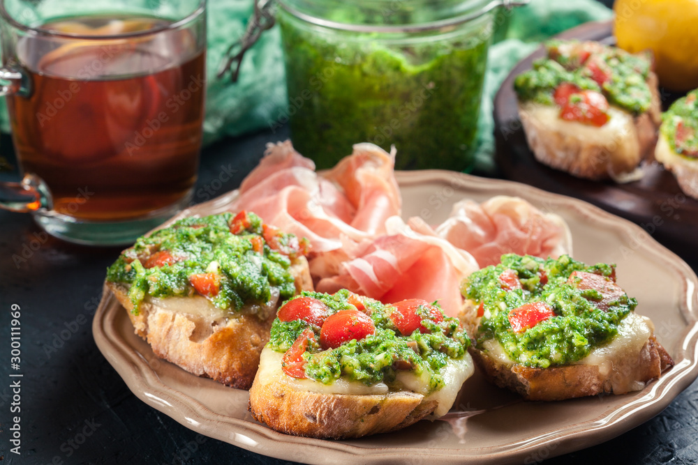 Bruschetta with fresh pesto, mozzarella and cherry tomatoes on a plate Bruschetta with fresh pesto, mozzarella and cherry tomatoes on a plate