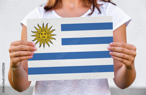 woman holds flag of Uruguay on paper sheet