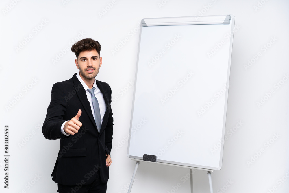 Young businessman giving a presentation on white board giving a presentation on white board with thumb up Young businessman giving a presentation on white board giving a presentation on white board with thumb up