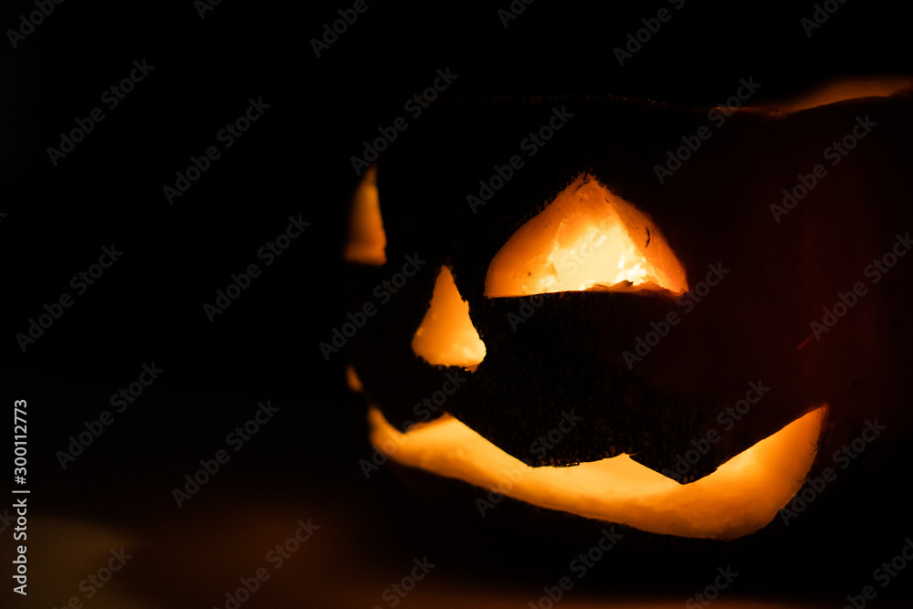 Fototapeta premium Alone head of the pumpkin inside the dark room. Only candle make a light during october halloween night.