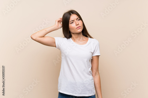 Pretty young girl over isolated background having doubts while scratching head