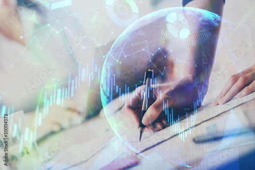 A woman hands writing information about stock market in notepad. Forex chart holograms in front. Concept of research. Multi exposure