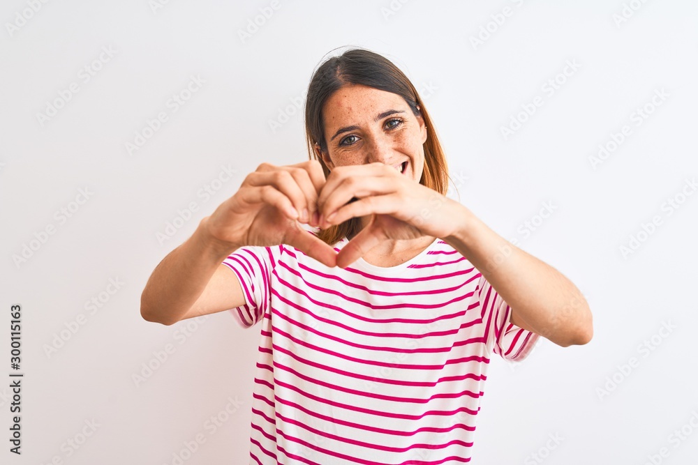 Beautiful redhead woman wearing casual striped pink t-shirt over isolated background smiling in love showing heart symbol and shape with hands. Romantic concept. Beautiful redhead woman wearing casual striped pink t-shirt over isolated background smiling in love showing heart symbol and shape with hands. Romantic concept.