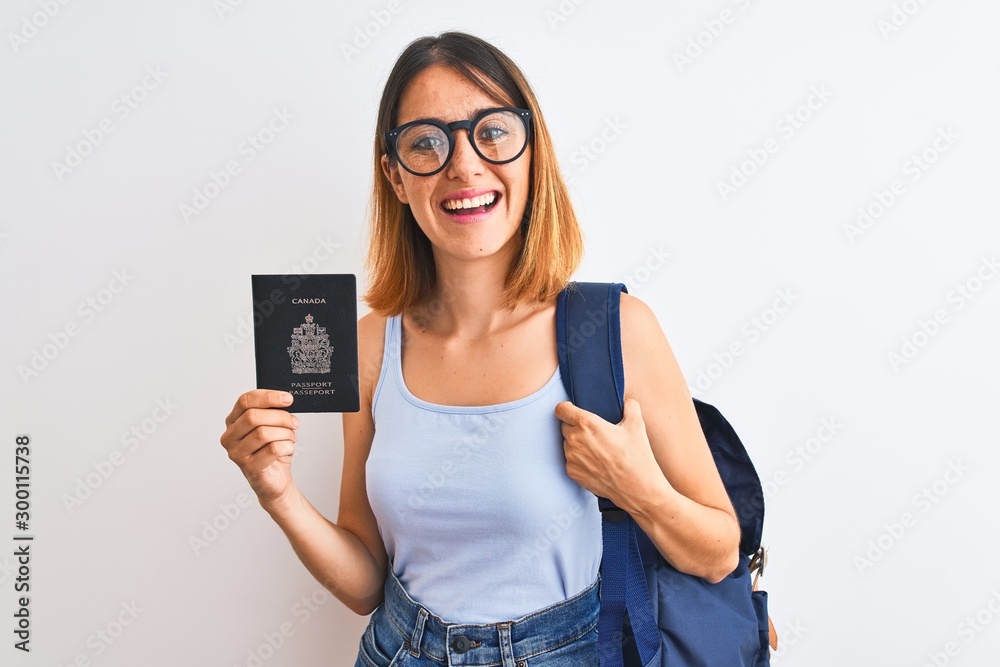 Beautiful redhead student woman wearing backpack and holding passport of canada with a happy face standing and smiling with a confident smile showing teeth