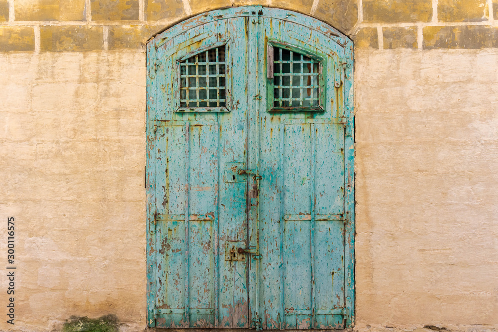 Vintage old warehouse blue wooden door with ancient limestone brick wall