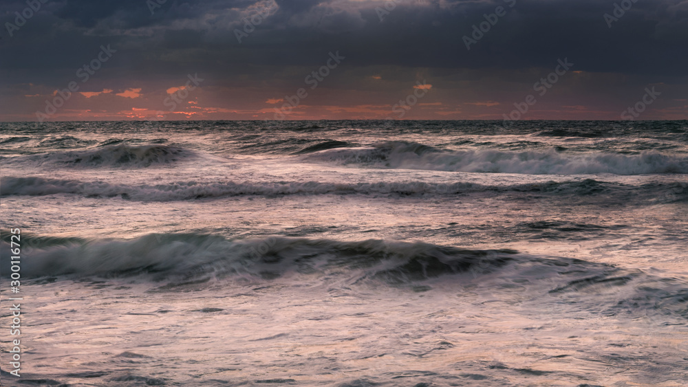 dramatic seascape sunset with cloudy sky and high surf long exposure