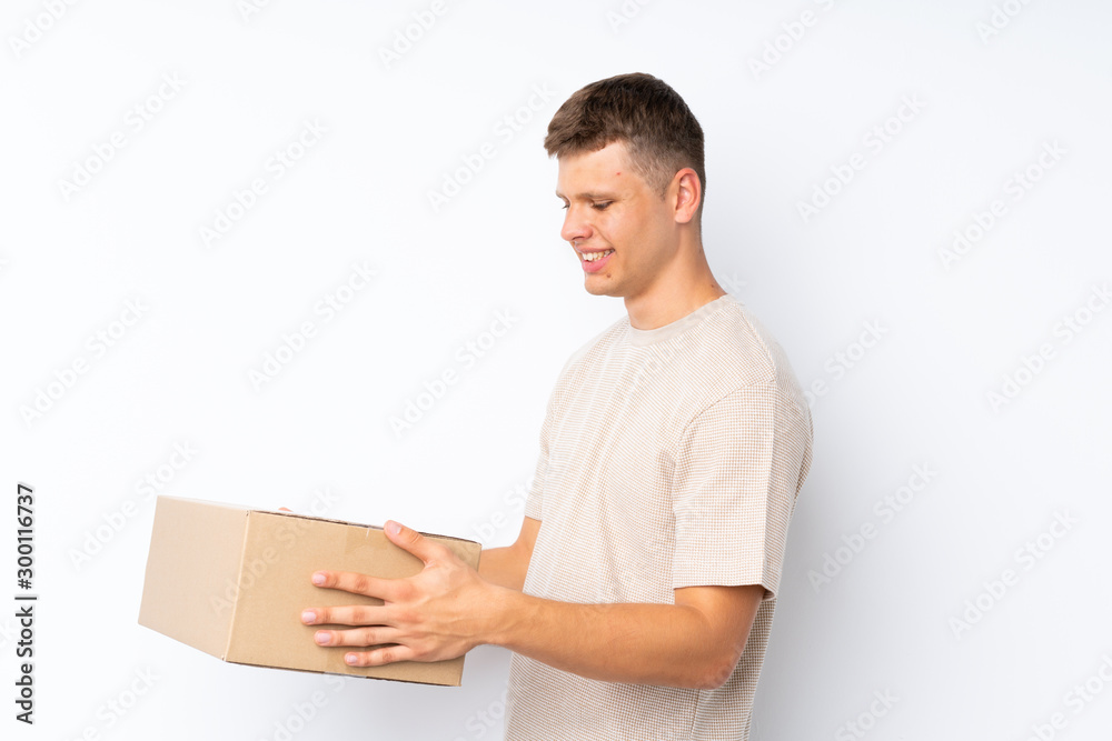 Young handsome man over isolated white background holding a box to move it to another site Young handsome man over isolated white background holding a box to move it to another site