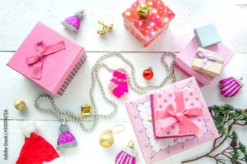 Christmas background top view. Pink and red gift boxes. Coniferous branches and Christmas toys on a background of a white wooden board. New Year 2020