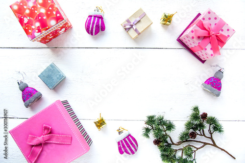 Christmas background top view. Pink and red gift boxes. Coniferous branches and Christmas toys on a background of a white wooden board. New Year 2020