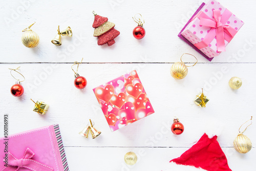Christmas background top view. Pink and red gift boxes. Coniferous branches and Christmas toys on a background of a white wooden board. New Year 2020