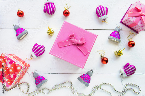 Christmas background top view. Pink and red gift boxes. Coniferous branches and Christmas toys on a background of a white wooden board. New Year 2020