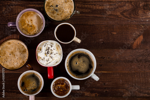 Lots of coffee in different cups on wooden table