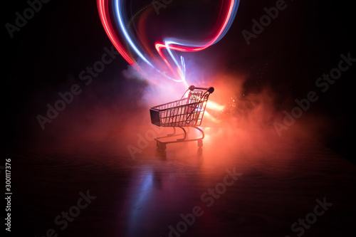 Empty shopping trolley on dark toned foggy background with some copy space. Financial crisis concept. photo