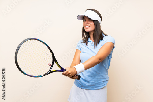 Young woman playing tennis over isolated background © luismolinero