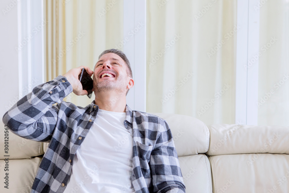 Caucasian man laughing while talking on a phone Caucasian man laughing while talking on a phone