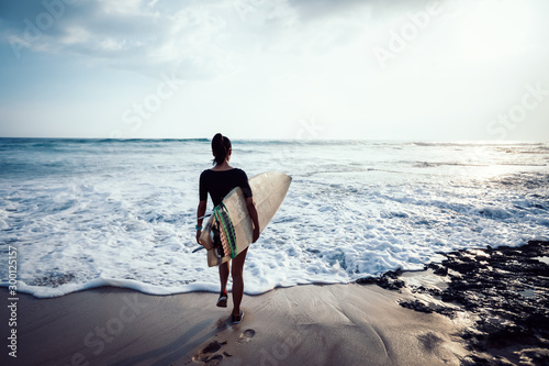 Photography Woman surfer with surfboard going to surf at seaside