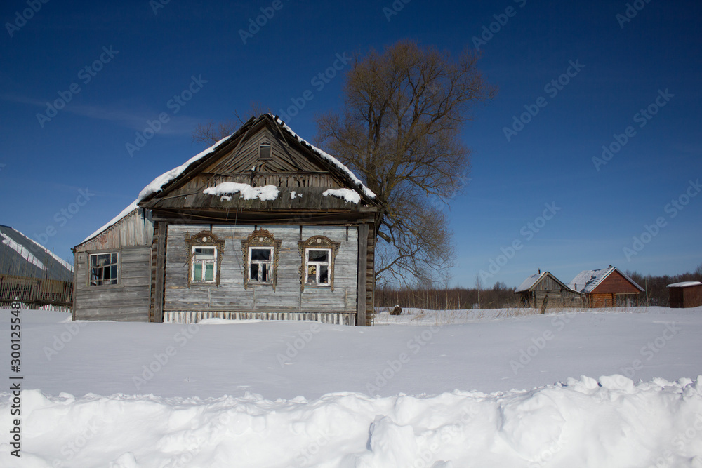 Old wooden house and snow drifts in winter in the village on a frosty Sunny day. Winter landscape. Russian village in winter.