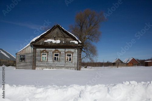 Old wooden house and snow drifts in winter in the village on a frosty Sunny day. Winter landscape. Russian village in winter.