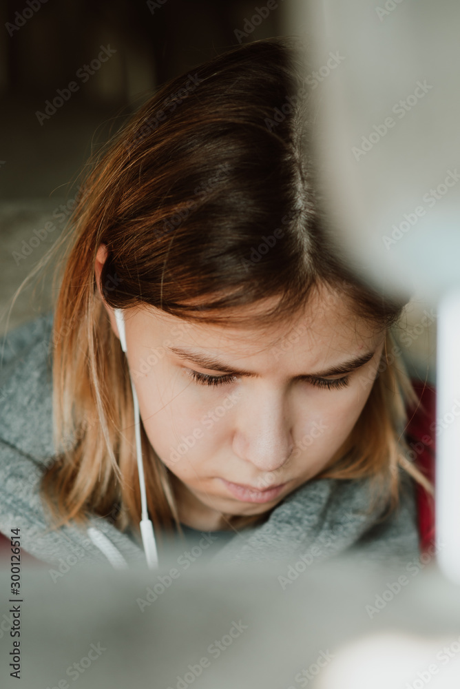 Close up of the face of a girl sitting in a car and listening to music through headphones.