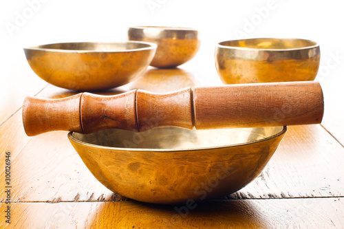 Closeup of four singing bowls and one mallet on a wooden table