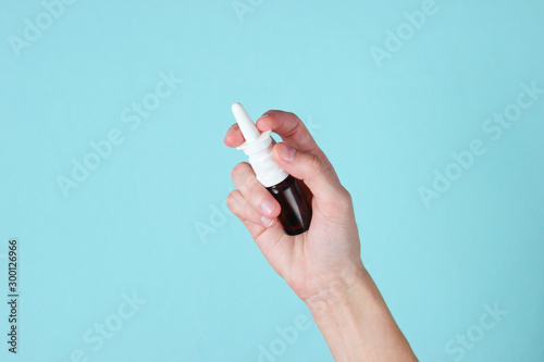 Female hand holds nasal spray on a blue background. Rhinitis treatment photo