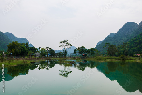 Mountains reflected in an ember green lake on the hidden Cat Ba Island which is regularly visited by boat tours around Ha Long Bay © Piranhi