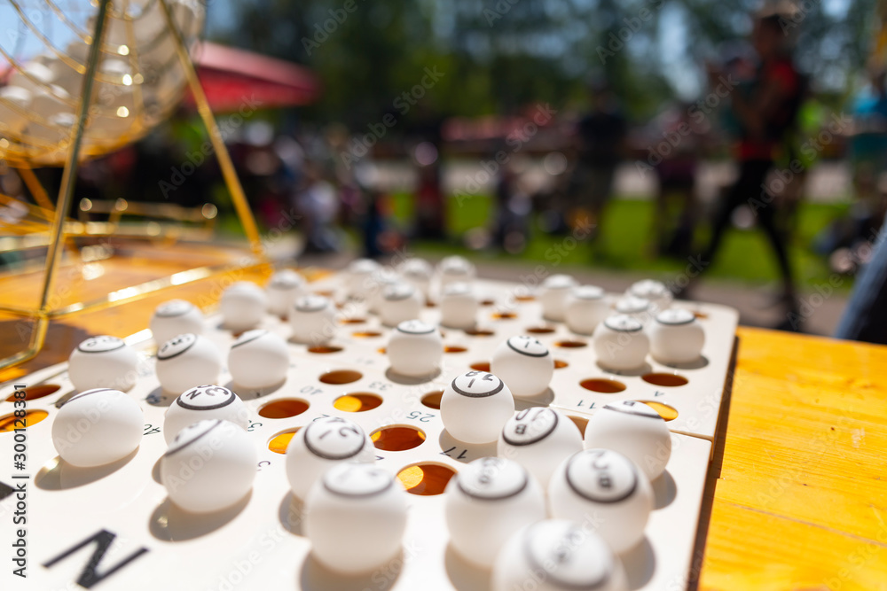 Bingo balls on a table next to a lotto raffle drum machine. Outdoor backyard setup at an event or party. Bingo balls on a table next to a lotto raffle drum machine. Outdoor backyard setup at an event or party.