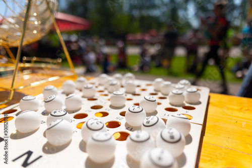 Bingo balls on a table next to a lotto raffle drum machine. Outdoor backyard setup at an event or party.