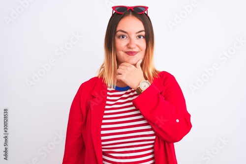 Young beautiful woman wearing striped t-shirt and jacket over isolated white background looking confident at the camera with smile with crossed arms and hand raised on chin. Thinking positive.