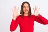 Young beautiful girl wearing red casual t-shirt standing over isolated white background showing and pointing up with fingers number ten while smiling confident and happy.