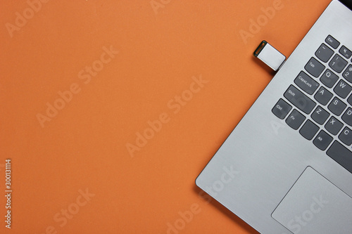 Vászonkép Laptop with flash drive on brown paper background
