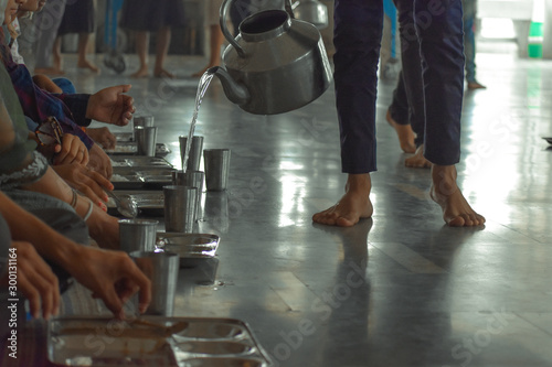 Without discriminating against race and color, people are sitting down together eating food called langar in local language in golden temple Amritsar, Punjab