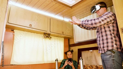 Boyfriend experiencing virtual reality goggles inside retro camper van photo