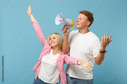 Εκτύπωση καμβά Young happy couple two friends guy girl in white pink empty t-shirts posing isolated on pastel blue wall background