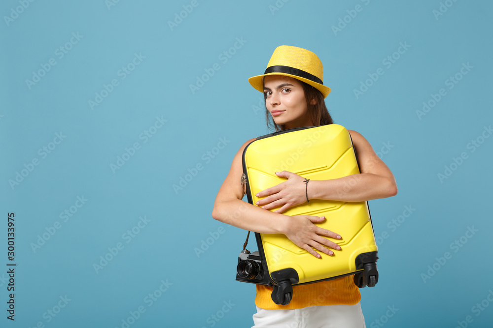 Traveler tourist woman in yellow casual clothes, hat with suitcase photo camera isolated on blue background. Female passenger traveling abroad to travel on weekends getaway. Air flight journey concept Traveler tourist woman in yellow casual clothes, hat with suitcase photo camera isolated on blue background. Female passenger traveling abroad to travel on weekends getaway. Air flight journey concept