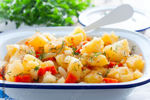 Baked sliced potatoes with carrots and onions in an enameled form, horizontal