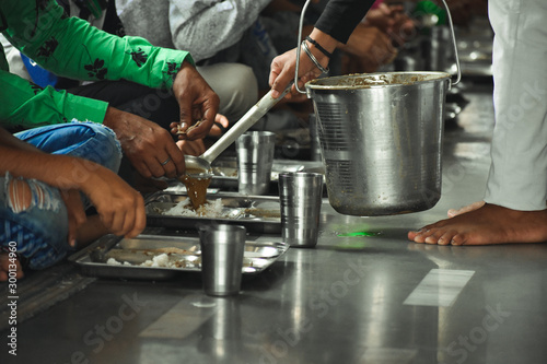 Without discriminating against race and color, people are sitting down together eating food called langar in local language in golden temple Amritsar, Punjab