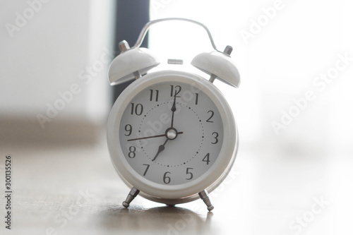 Alarm clock on wooden table with grey background, selective