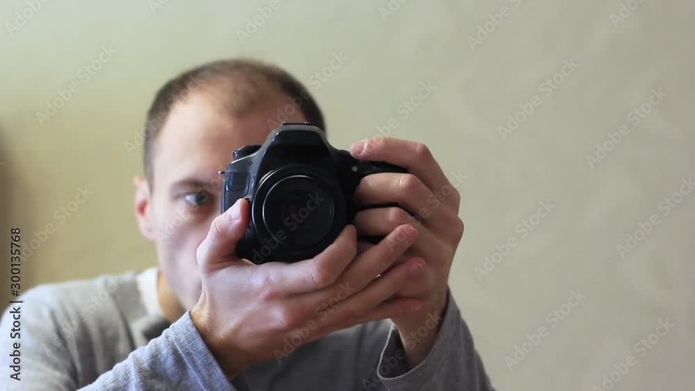 Young guy photographer with a camera in the reflection of the mirror. Young guy photographer with a camera in the reflection of the mirror.