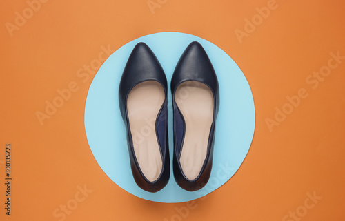Classic women’s high heel shoes on brown background with blue pastel circle in the middle. Stylish shoes. Minimalistic fashion still life. Top view
