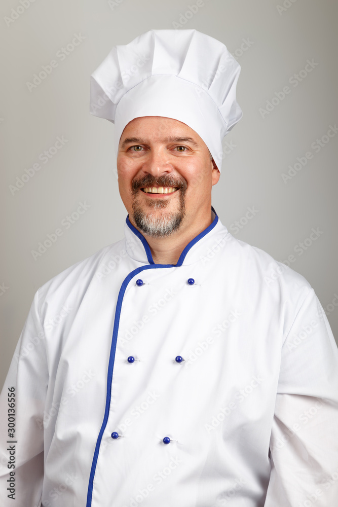Portrait of a smiling professional chef cook man dressed a chef uniform, grey background Portrait of a smiling professional chef cook man dressed a chef uniform, grey background