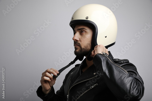 Close up portrait of young and handsome biker fasten up his helmet.