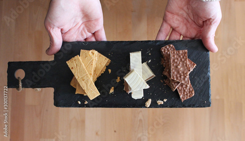 Person offering three types of Spanish turron on a slate