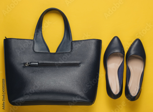 Classic high heel shoes, leather bag on yellow background. Minimalism fashion concept. Top view