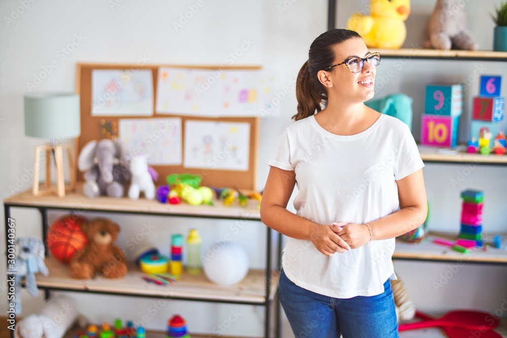 Young beautiful teacher wearing glasses standing at kindergarten Young beautiful teacher wearing glasses standing at kindergarten
