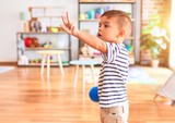 Beautiful toddler boy playing with colored small balls at kindergarten