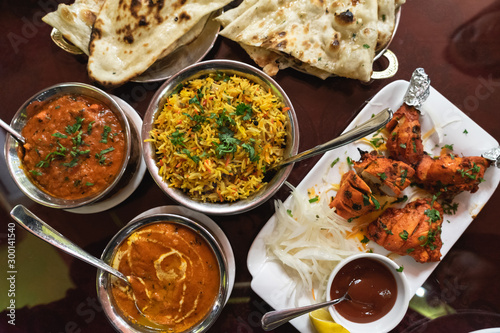 Assortment of Indian dishes for dinner, butter chicken, tikka masala, rice and naan