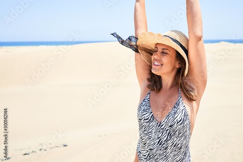 Young beautiful woman sunbathing with open arms wearing summer swinsuit at maspalomas dunes bech photo